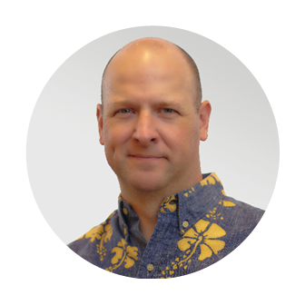 Smiling headshot of Mike Fogle, President of Nakupuna Solutions and Nakupuna Federal at Nakupuna Companies, in a purple and yellow aloha shirt.