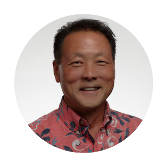 Smiling headshot of Wain Iwaki, Vice President of Na Ali'i at Nakupuna Companies, with short brown hair and a pink floral shirt.