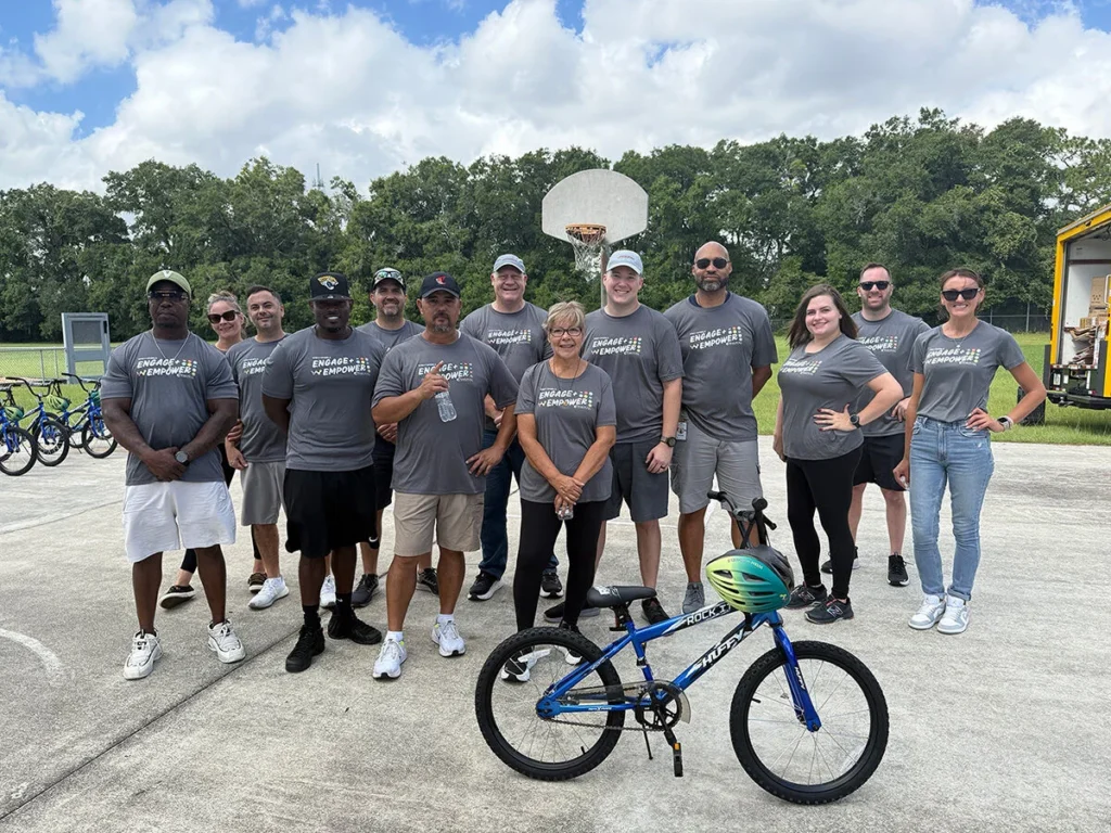 Nakupuna Company employees stand with newly assembled bikes, wearing matching gray "Engage & Empower" t-shirts for the Wish for Wheels Project Kupu event in partnership with Nakupuna Foundation.