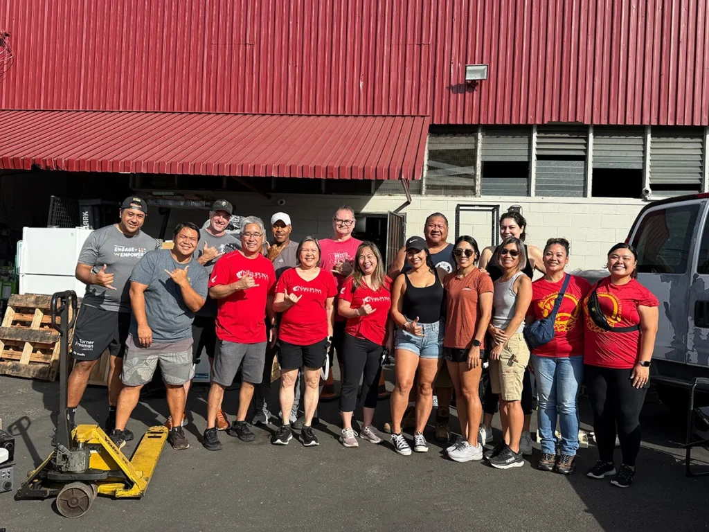 Hawaiian Hope Project Kupu Nakupuna Companies Nakupuna employees volunteer with Wish for Wheels Hawai'i, one of Hawaii's most charitable companies. A group of smiling Nakupuna team members pose in red shirts outside a warehouse, ready to build bikes for kids as part of their community giving initiative. This image is featured on the Nakupuna Companies website.