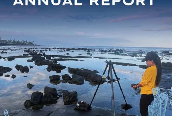 Nakupuna Foundation 2025 Annual Report cover: Two women document a rocky coastline at sunset, one with a tripod and camera, the other working on a laptop. This image is featured on the Nakupuna Companies website.